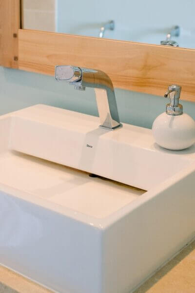 bathroom-Wash-Basin A clean bathroom sink featuring a white faucet and a mirror above it.