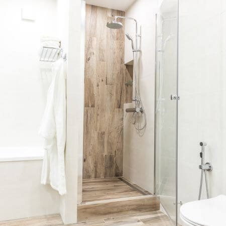 Bathroom-Conversion-4 A bathroom featuring a shower, toilet, and wooden flooring, creating a warm and inviting atmosphere.
