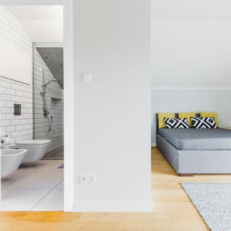 Bathroom Conversion 5 A bedroom featuring a bed, toilet, and sink, showcasing a bathroom conversion design.